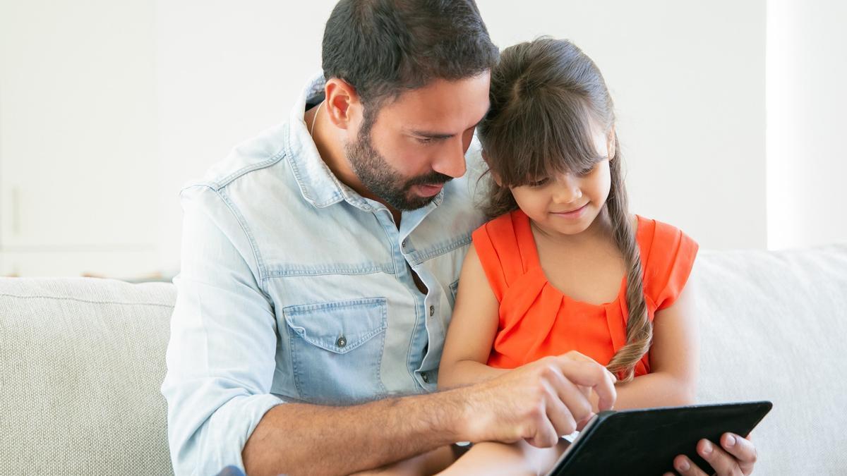 Un padre y su hija comparten tiempo y tablet.