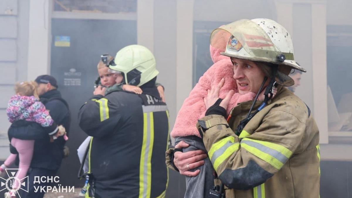 Bomberos ucranianos sostienen a varios de los niños evacuados.