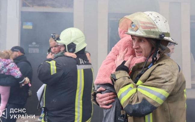 Bomberos ucranianos sostienen a varios de los niños evacuados.