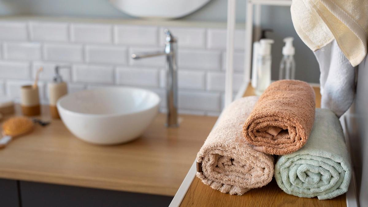 Toallas enrolladas sobre la estantería de un baño.