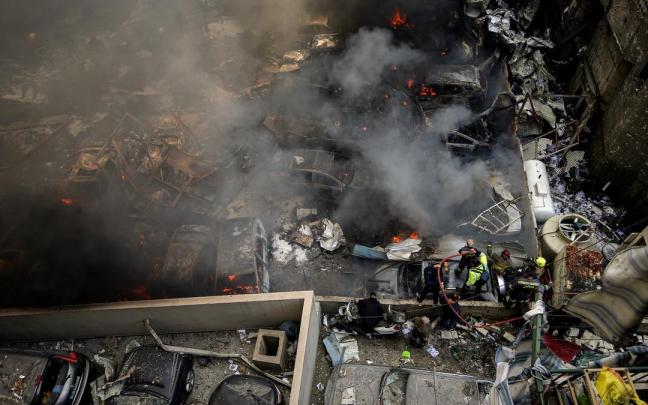Los bomberos extinguen un incendio en un lugar afectado por un ataque aéreo israelí en Beirut.