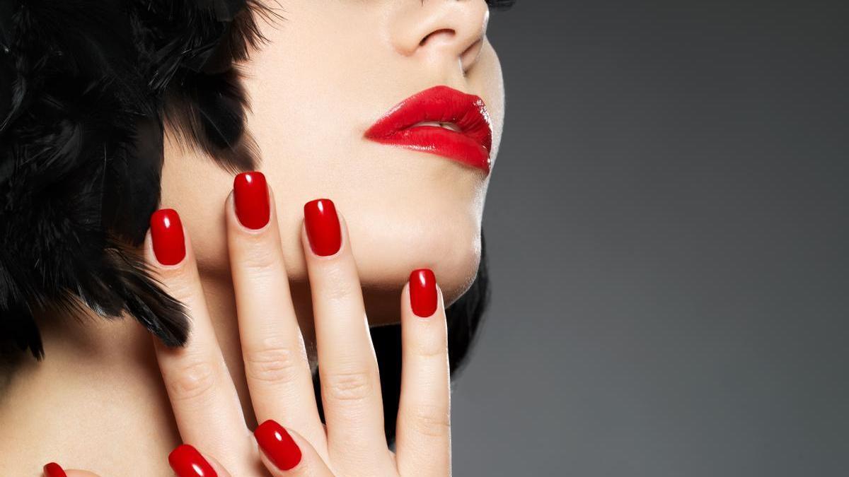 Una modelo posa con sus uñas rojas y labios a juego.