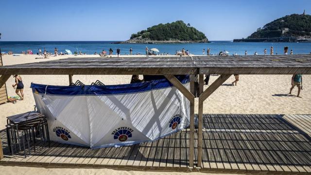 La Ertzaintza acordona con un biombo el cuerpo del hombre fallecido en la playa de Ondarreta / Javier Etxezarreta