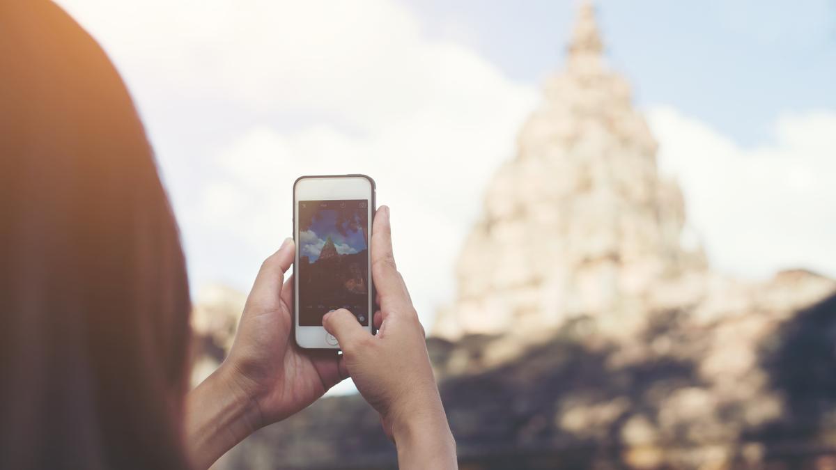 Mujer saca foto a un templo asiático.