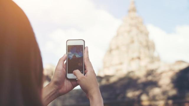 Mujer saca foto a un templo asiático.