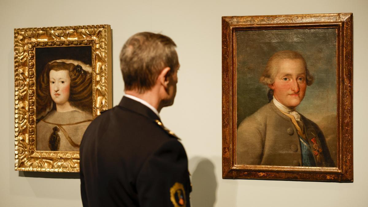 Un agente de la Unidad de Patrimonio de la Policía de la Generalitat Valenciana contempla los cuadros falsificados de Velázquez 'Mariana de Austria' y de Goya 'Carlos IV'.