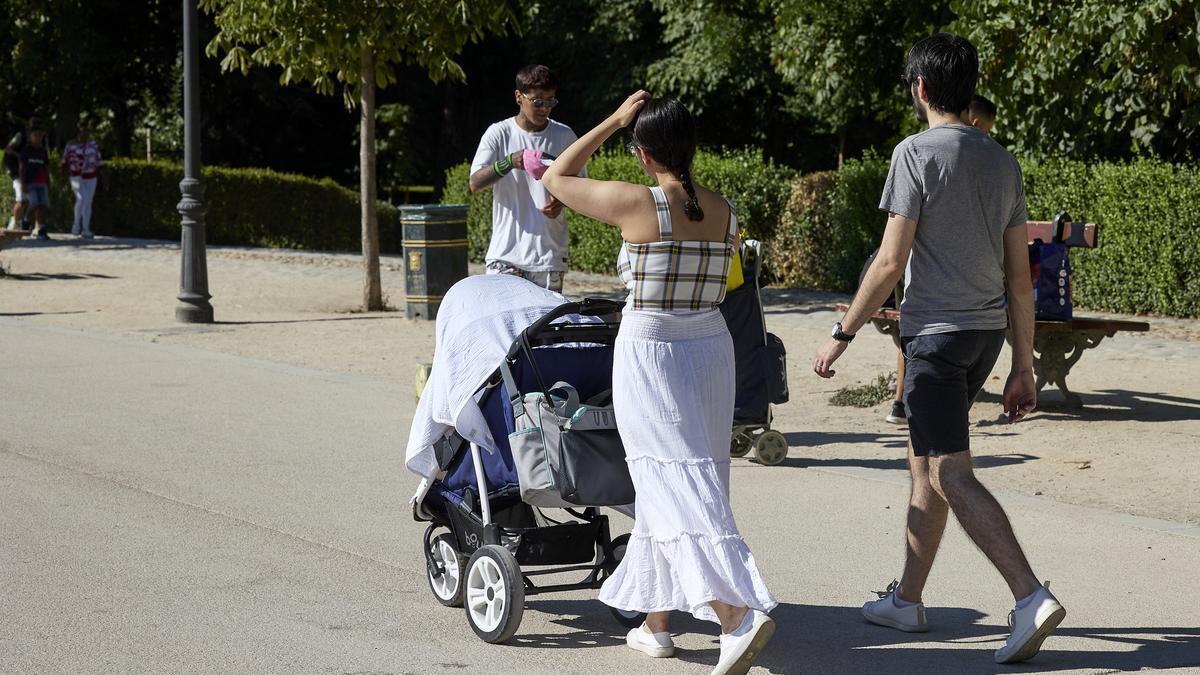 Una pareja pasea con un carrito de bebé por el madrileño parque de El Retiro.