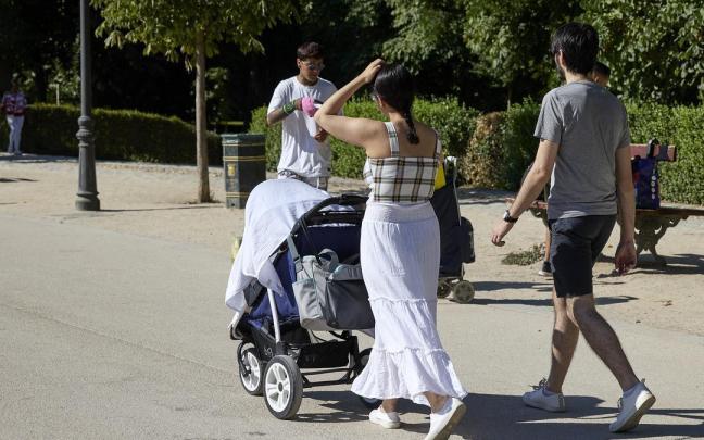 Una pareja pasea con un carrito de bebé por el madrileño parque de El Retiro.