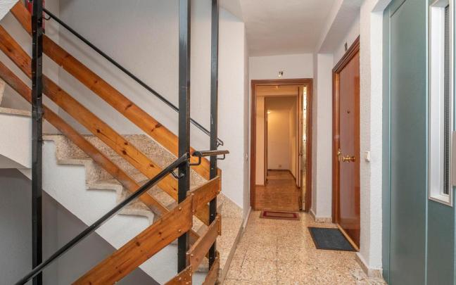 Rellano de escalera con la puerta de una vivienda abierta.