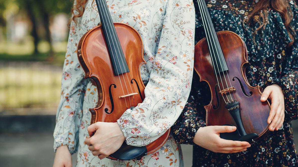 Dos personas sujetando dos violines, en una imagen de archivo.