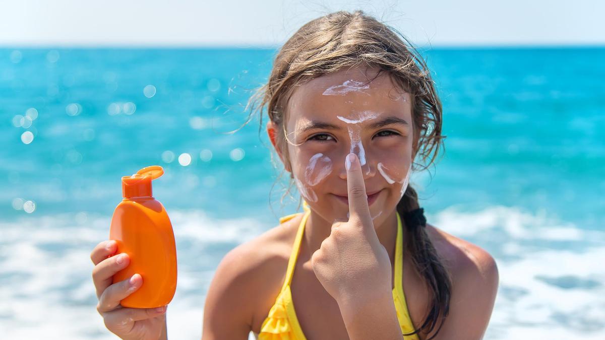 Una niña se protege con una crema solar.