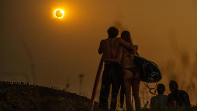Unos surfistas contemplan el eclipse solar total desde la playa cántabra de Ajo.