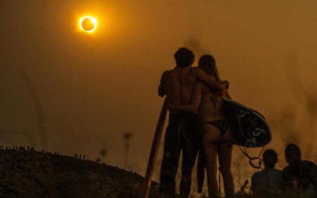 Unos surfistas contemplan el eclipse solar total desde la playa cántabra de Ajo.
