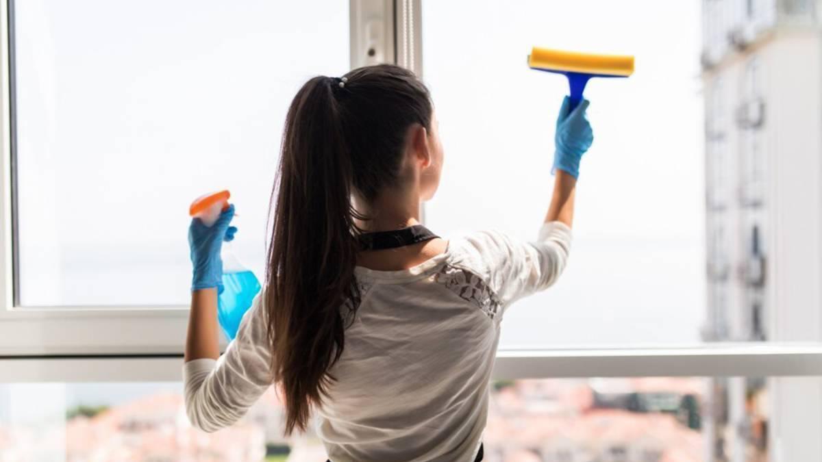 Chica limpia las ventanas de su casa