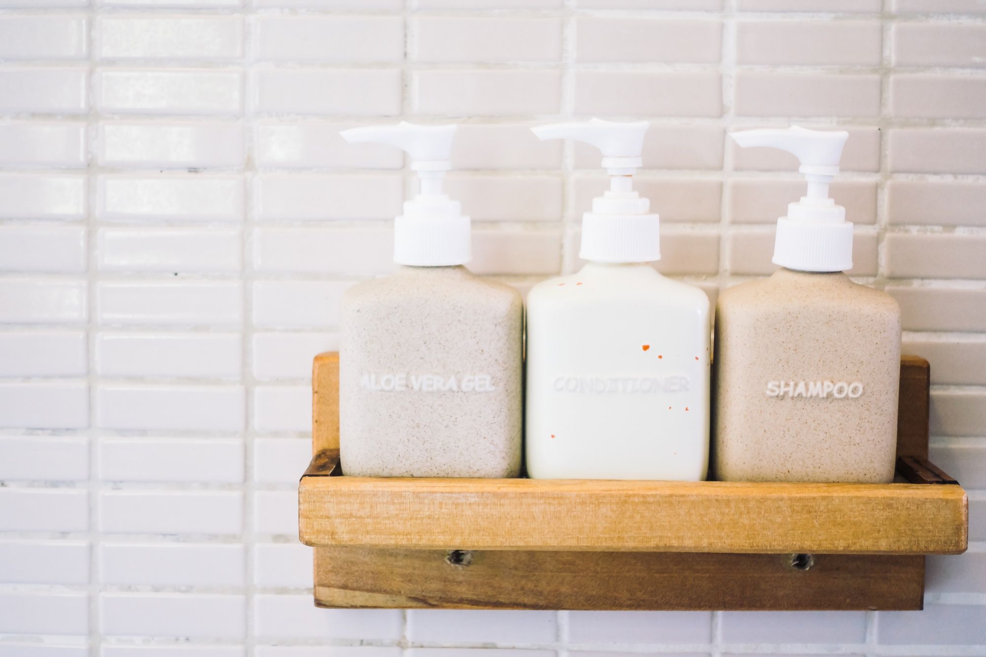 Champú, gel y crema hidratante en una estantería de ducha.