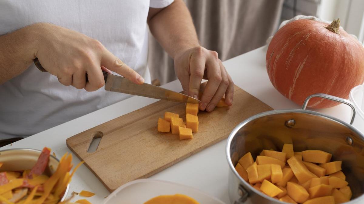 Chica corta una calabaza en trozos con ayuda de un cuchillo.