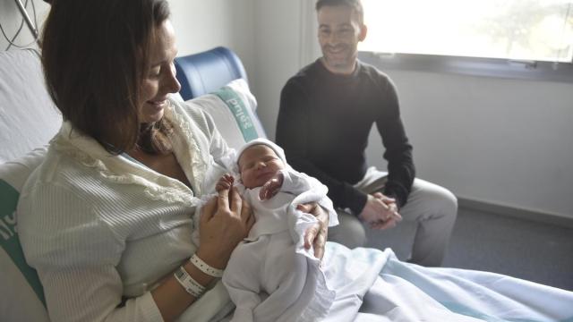 Una pareja posa con su hija recién nacida en un hospital.