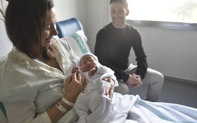 Una pareja posa con su hija recién nacida en un hospital.