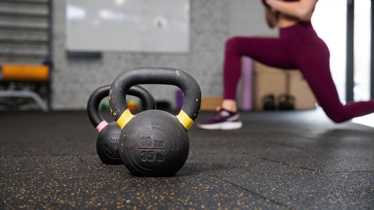 Persona en el gimnasio usando kettlebells