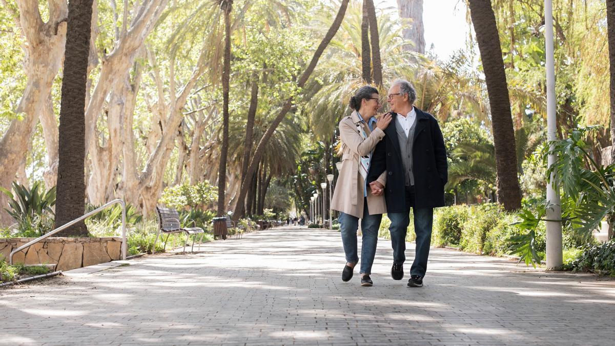 Una pareja de jubilados pasea por un parque.
