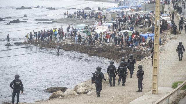 Agentes de la Policía Nacional intervienen durante el proceso de desalojo del embolsamiento de migrantes en la playa de El Trampolín.