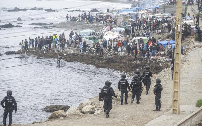 Agentes de la Policía Nacional intervienen durante el proceso de desalojo del embolsamiento de migrantes en la playa de El Trampolín.