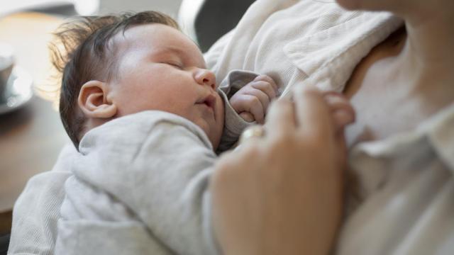 Bebé duerme en brazos de su madre.