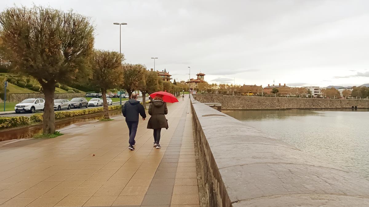 Dos personas se cubren de la lluvia en el paseo de Ereaga, en Algorta.