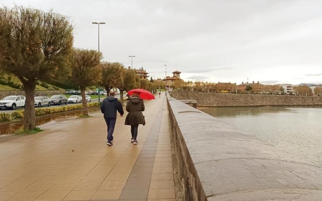 Dos personas se cubren de la lluvia en el paseo de Ereaga, en Algorta.