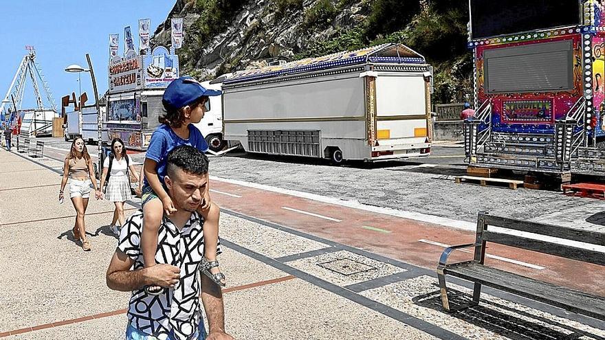 Un hombre y su hija pasan junto a las atracciones aún cerradas.