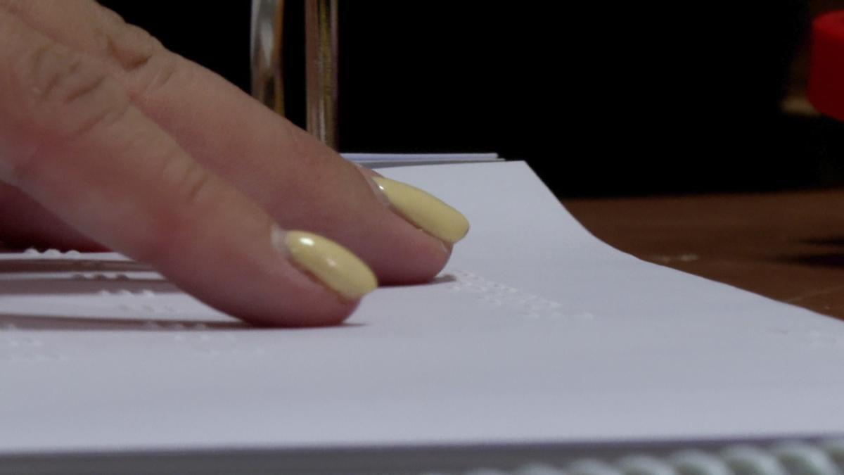 Una mujer ciega leyendo Braille