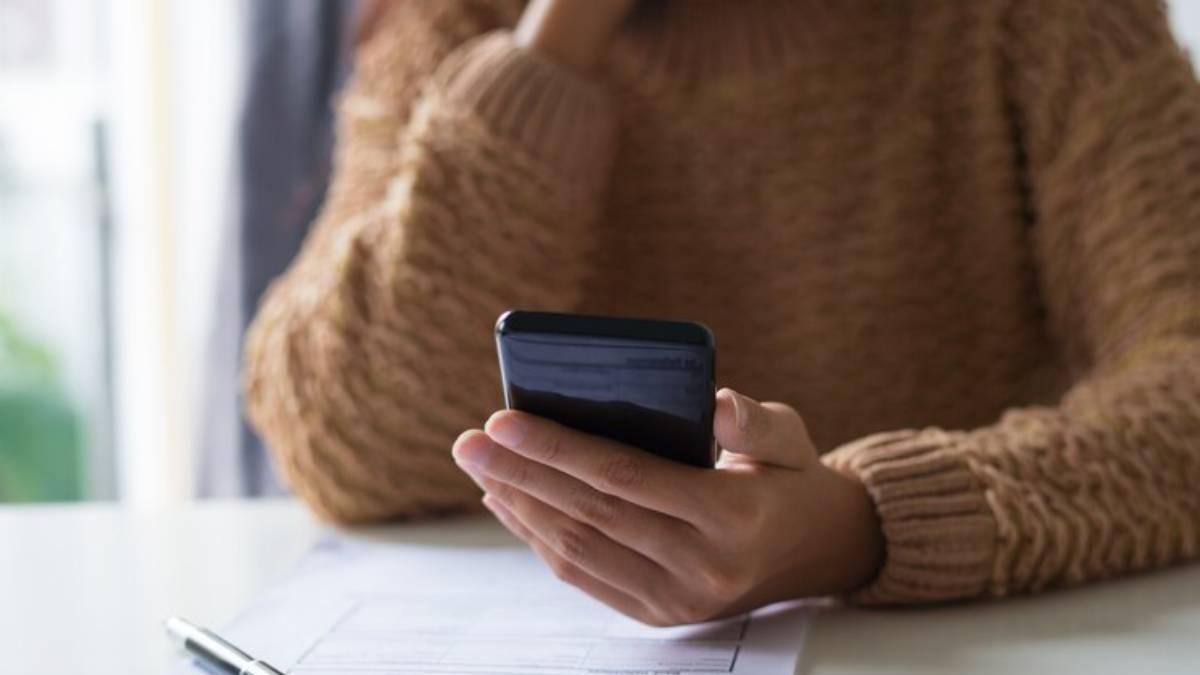 Hombre revisa la factura de su compañía en su teléfono móvil.
