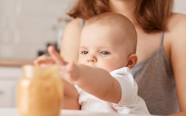 Imagen de archivo de un bebé cogiendo un potito.