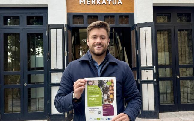 Inaxio Illarramendi con el cartel de la exposición itinerante, fuera del mercado de Zarautz.