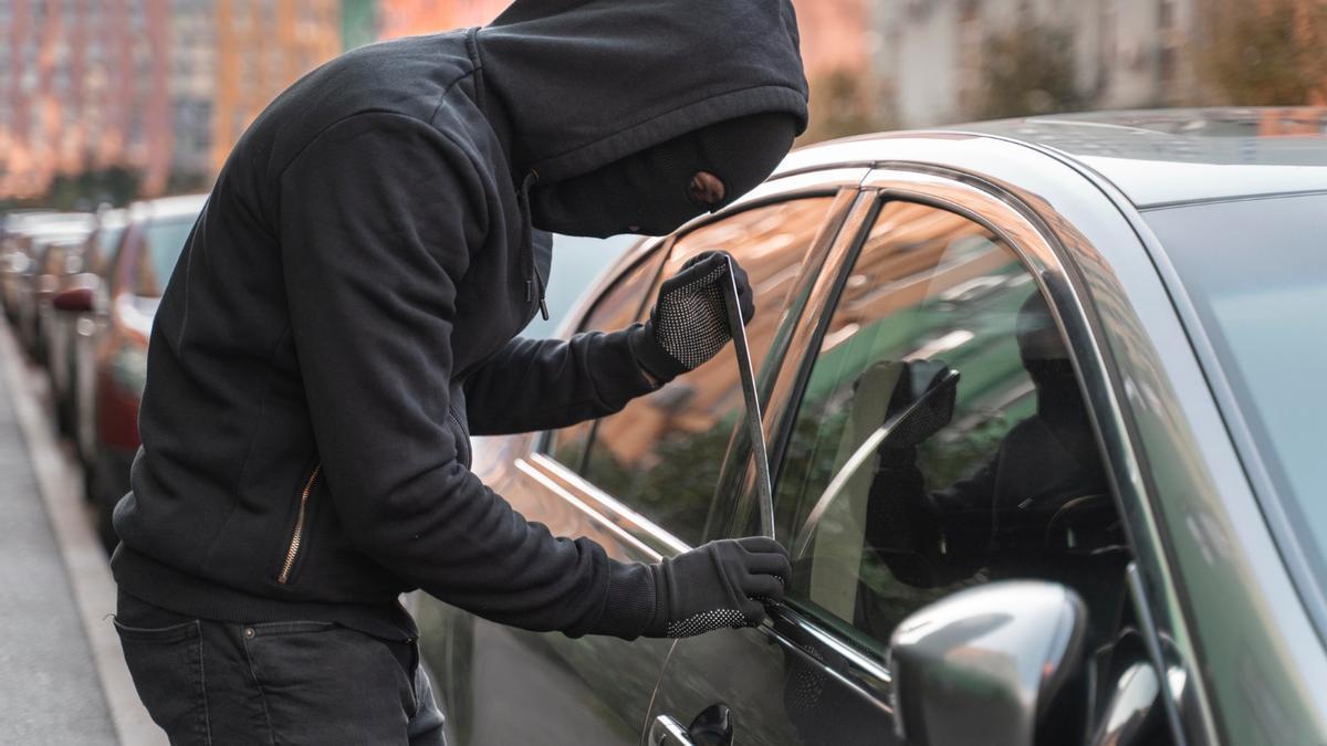 Un ladrón, intentando entrar en un coche.