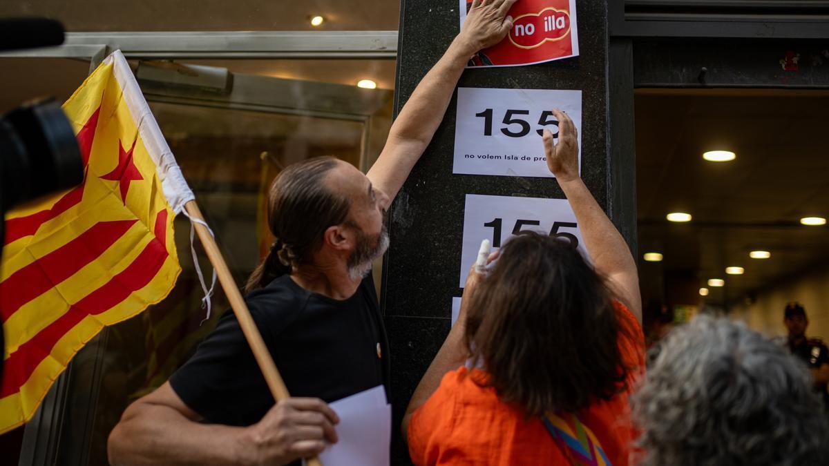 Activistas pegan carteles contra la investidura de Illa ante la sede de ERC.