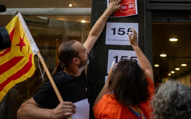 Activistas pegan carteles contra la investidura de Illa ante la sede de ERC.