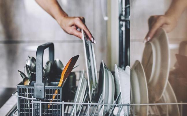 Una mujer coloca un plato en el lavavajillas.