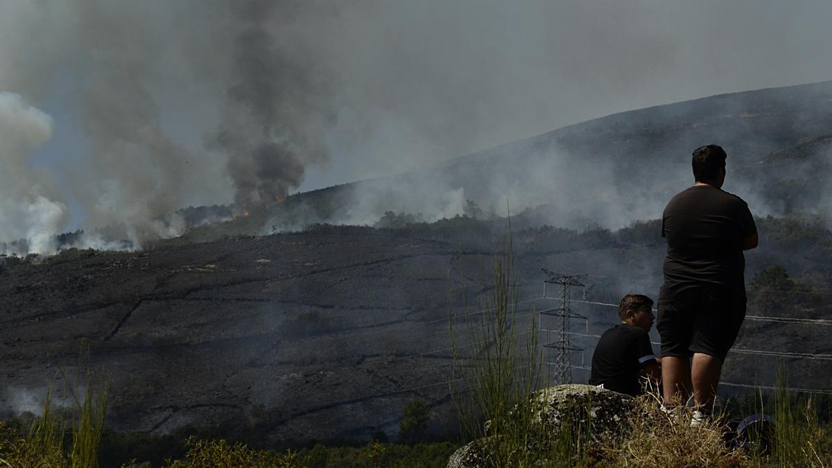 Imagen de archivo de dos personas contemplando los incendios en Galicia en 2022.