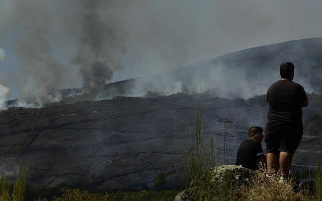 Imagen de archivo de dos personas contemplando los incendios en Galicia en 2022.