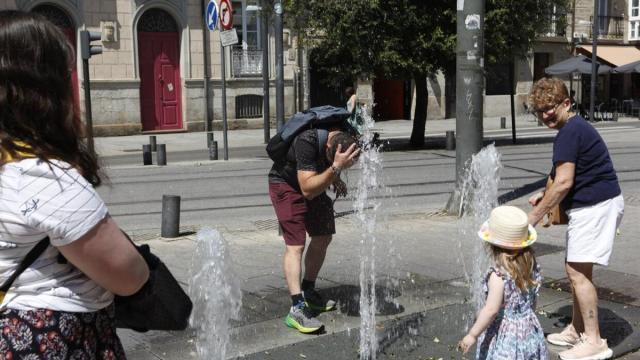 Varias personas se refrescan en una fuente durante una ola de calor.