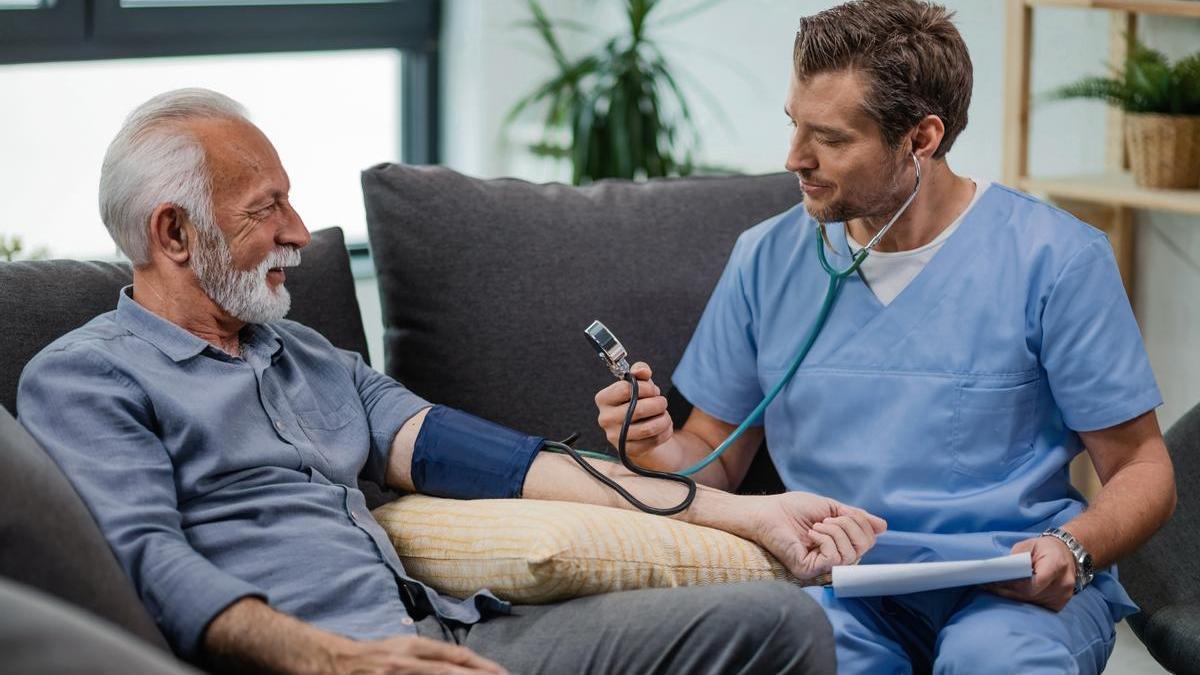 Médico revisa la tensión arterial a un señor mayor.