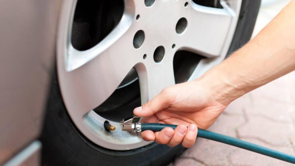 Pirmer plano de las manos de un hombre hinchando las ruedas de su coche en una gasolinera.