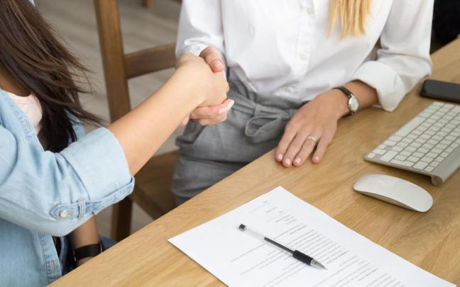 Una mujer estrecha la mano después de firmar su renuncia.