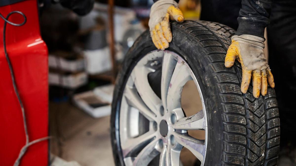 Un trabajador comprueba el estado de una rueda en un taller.