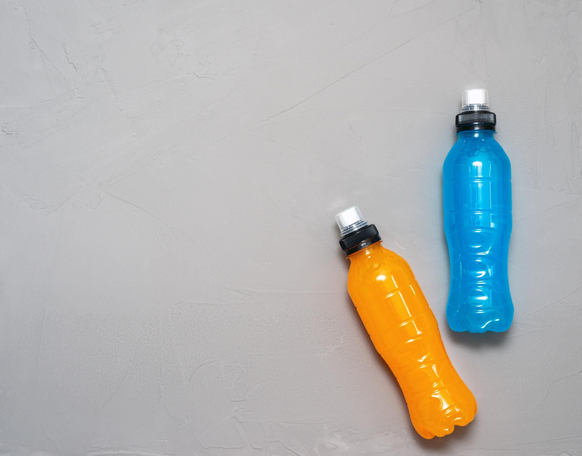 Dos botellas de bebida isotónica de color naranja y azul.