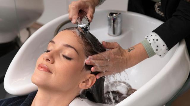 Una peluquera lava el pelo a una mujer en un centro de belleza.