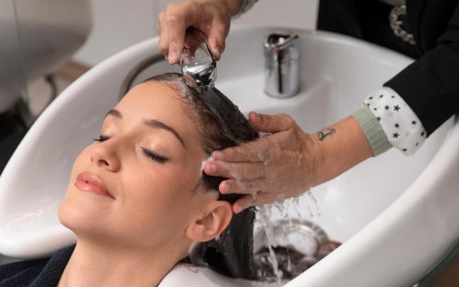 Una peluquera lava el pelo a una mujer en un centro de belleza.