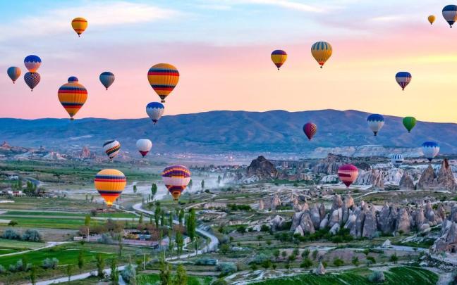 Decenas de coloridos globos sobrevuelan el paisaje rocoso de la Capadocia.