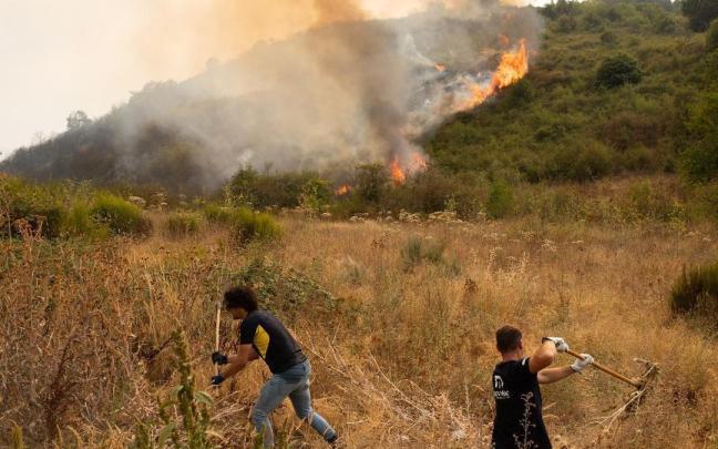 Los vecinos ayudan a evitar la propagación del fuego de un incendio en León.